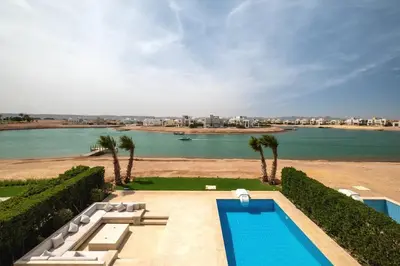 a swimming pool with a view of a body of water at Luxury 4BR + Nanny Villa • Ancient Sands in Hurghada