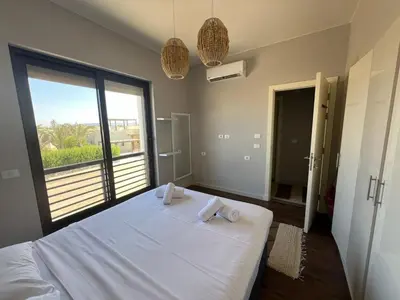 a bedroom with a white bed with a large window at Chic Cyan 3BR Apt. • Prime Location in Hurghada