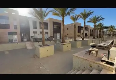 a courtyard with palm trees in front of a building at Stylish 1BR • Scarab Main Pool Access in Hurghada