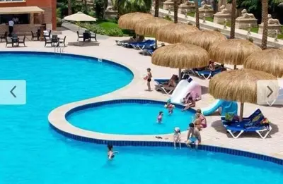 a group of people in a swimming pool with umbrellas at ميراج باي in Hurghada
