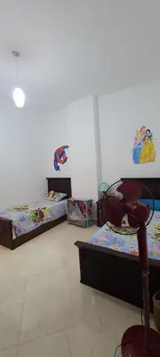 a room with two beds and a chair in it at Luxury Two Bedrom Apartment in Hurghada
