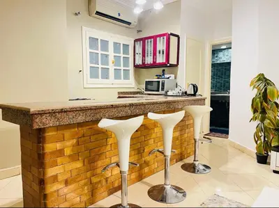 a kitchen with two white stools at a counter at Sheraton St in Hurghada