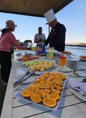 a buffet of food with oranges on a table at Five Stars Nile Cruise from Luxor to Aswan 4 nights in Aswan