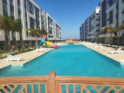 a large pool with a slide in the middle of a building at Fanader bay sea view apartment in Hurghada