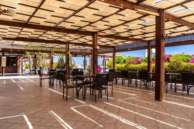 a patio with tables and chairs under a wooden pergola at Abu Dabbab Lodge in Abu Dabab