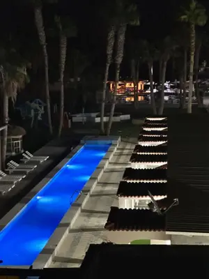 a swimming pool with a row of black and white chairs at Mashrabiya one bed room apartment in Hurghada