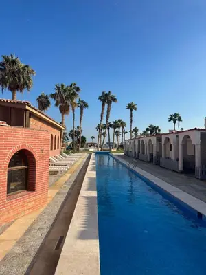 a swimming pool with palm trees next to a building at Mashrabiya one bed room apartment in Hurghada