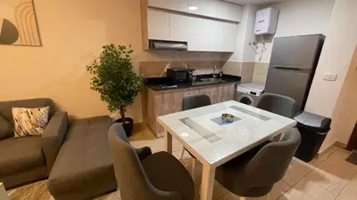 a living room with a table and a kitchen at Dani Apartment at Aldau Heights in Hurghada