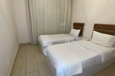 two beds in a hotel room with white sheets at Family apartment Aldau Heights in Hurghada