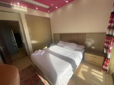 a small bedroom with a bed with white sheets at Galaxy Aldau heights 2 bedrooms in Hurghada