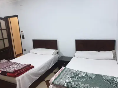 two beds in a small room with white walls at El Quarn Apartment in ‘Ezbet Abu Ḥabashi