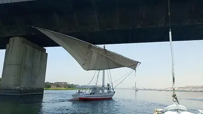 a boat in the water under a bridge at Nuba Tod Sailling boat in Aswan
