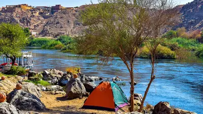 a tent on the rocks next to a river at ASSINGAR camp in Jazīrat Suhayl