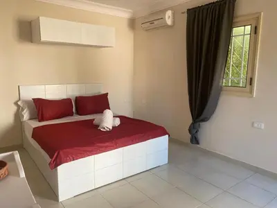 a bedroom with a bed with red sheets and a window at Hurghada-Magawish Studio 1 in Hurghada