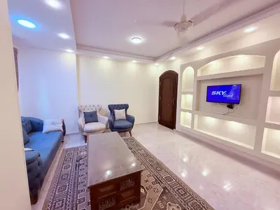 a living room with a blue couch and a tv at Sheherazade Guesthouse in Luxor