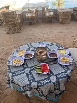 a table with plates of food on the beach at sunset guest house in Aswan