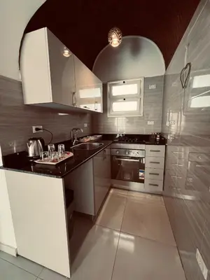 a kitchen with white cabinets and a black counter top at Rooftop in Hurghada with seaview and private terrace in Hurghada