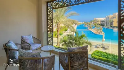 a balcony with chairs and a table and a view of the water at Ollystays Mangroovy Seaview 2BR Beach and Pool Free access in Hurghada