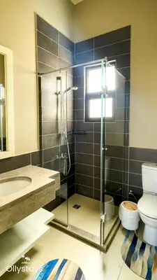 a bathroom with a shower and a toilet and a sink at Ollystays Tawila 2BR Apt Shared pool El Gouna in Hurghada