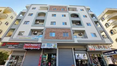 a tall white building with shops in front of it at الغردقه in Hurghada