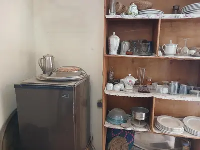 a kitchen with a shelf with dishes and a refrigerator at Habu view in Al Karnak