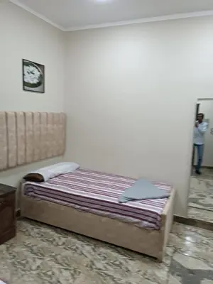 a bed in a bedroom with a person in the background at فندق الإيمان El Eman Hotel in Maḩaţţat Idfū