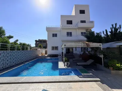 a house with a swimming pool in front of a building at Sylvie guest house in Luxor