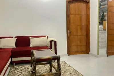 a living room with a red couch and a wooden door at El Hady villa with swimming pool in Luxor