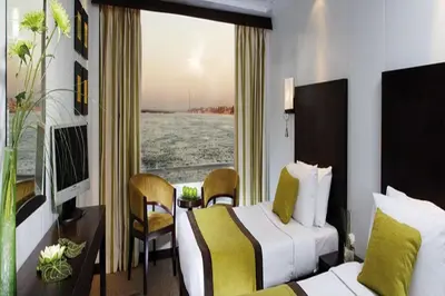 a hotel room with two beds and a window at Nile Cruise FB 3 Nights Aswan Luxor in Aswan