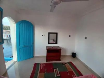 a room with a blue door and a table and a mirror at Nile Bride in Aswan