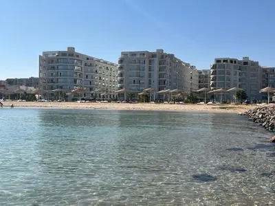 a beach with umbrellas and buildings and the water at scandic resort sea view in Hurghada