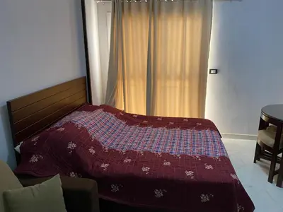 a bedroom with a bed with a red comforter and a window at Tiba A F B View in Hurghada