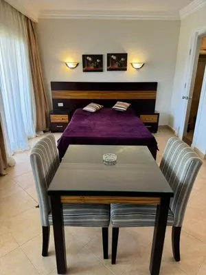 a bedroom with a bed and a table and two chairs at Cozy Sunny Studio with Pool View - Sahl Hasheesh in Hurghada