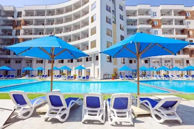 a group of chairs and umbrellas next to a swimming pool at Tiba Golden Resort one bedroom in Hurghada