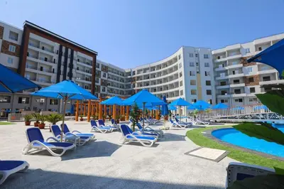 a group of chairs and blue umbrellas next to a pool at Tiba Golden Resort one bedroom in Hurghada