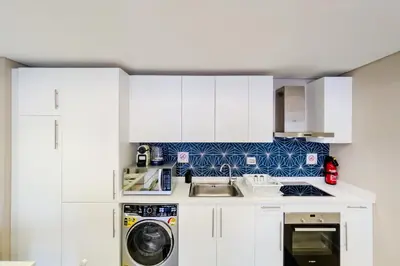 a kitchen with white cabinets and a washing machine at Homestyle & Summery 1BDR Mangroovy Free Beach Pool in Hurghada