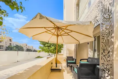 a patio with a large umbrella on a balcony at Homestyle & Summery 1BDR Mangroovy Free Beach Pool in Hurghada