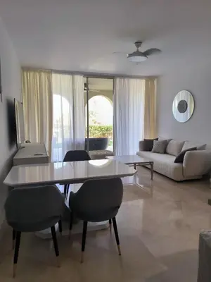 a living room with a table and chairs and a couch at Elite 3bdr apartment with garden beside corral reef in Hurghada