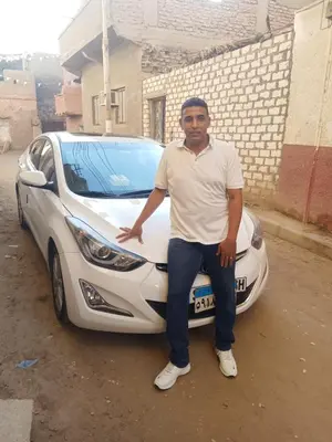 a man sitting on the front of a white car at مطار الاقصر in Luxor