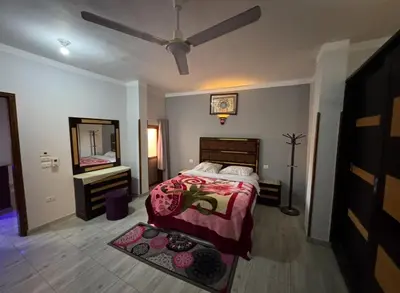 a bedroom with a bed and a dresser and a mirror at The Highlander in Al Karnak
