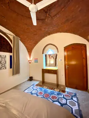 a room with a bed and a wooden door at ELamir house in Al Aqālitah
