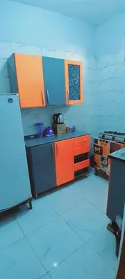 a kitchen with orange and blue cabinets and a refrigerator at Toko Sola in Jazīrat Suhayl