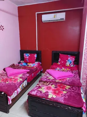 two beds in a room with red walls at Mahmoud's House in Al Manshīyah