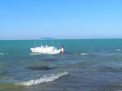 a woman standing in the ocean next to a boat at Beachfront Boho Style apartment in Fanadir Bay in Hurghada