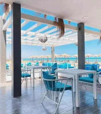 a dining room with blue chairs and tables and the ocean at Beachfront Boho Style apartment in Fanadir Bay in Hurghada