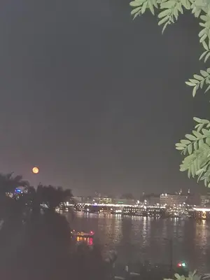a view of a river at night with the moon at Tut in Luxor