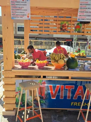 two people standing at a counter with fruits and vegetables at Beach front 2BR at elkarma hotel & aqua park in Hurghada