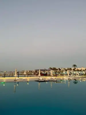 a pool of water with chairs and umbrellas on a beach at منتجع سكانديك in Hurghada