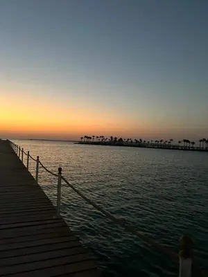 a boardwalk leading into the ocean at sunset at منتجع سكانديك in Hurghada