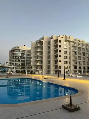 a swimming pool in front of a large apartment building at منتجع سكانديك in Hurghada